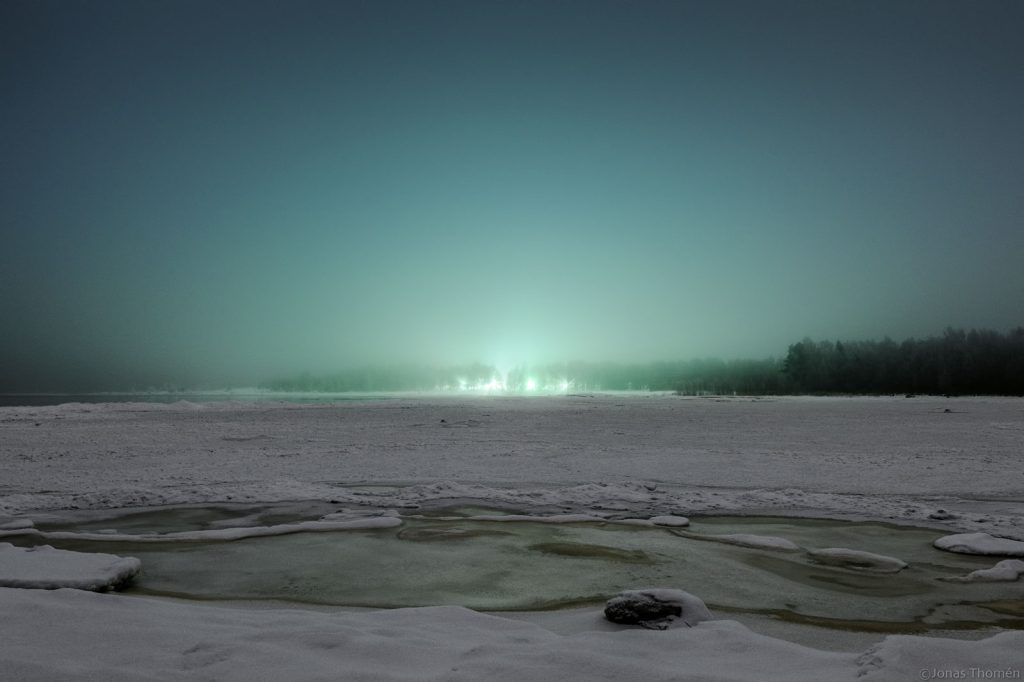 Green lit fog at night over the ice